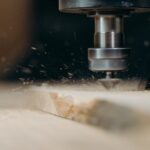 CNC machine in action, precisely cutting a wooden panel with sawdust flying.